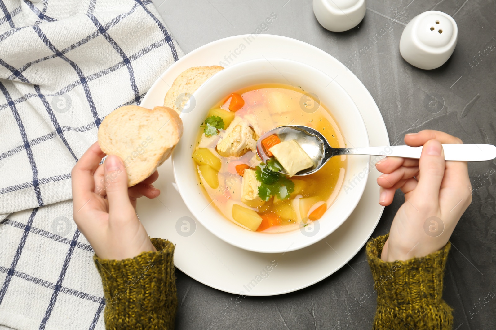 Photo of Woman eating fresh homemade chicken soup at table, top view