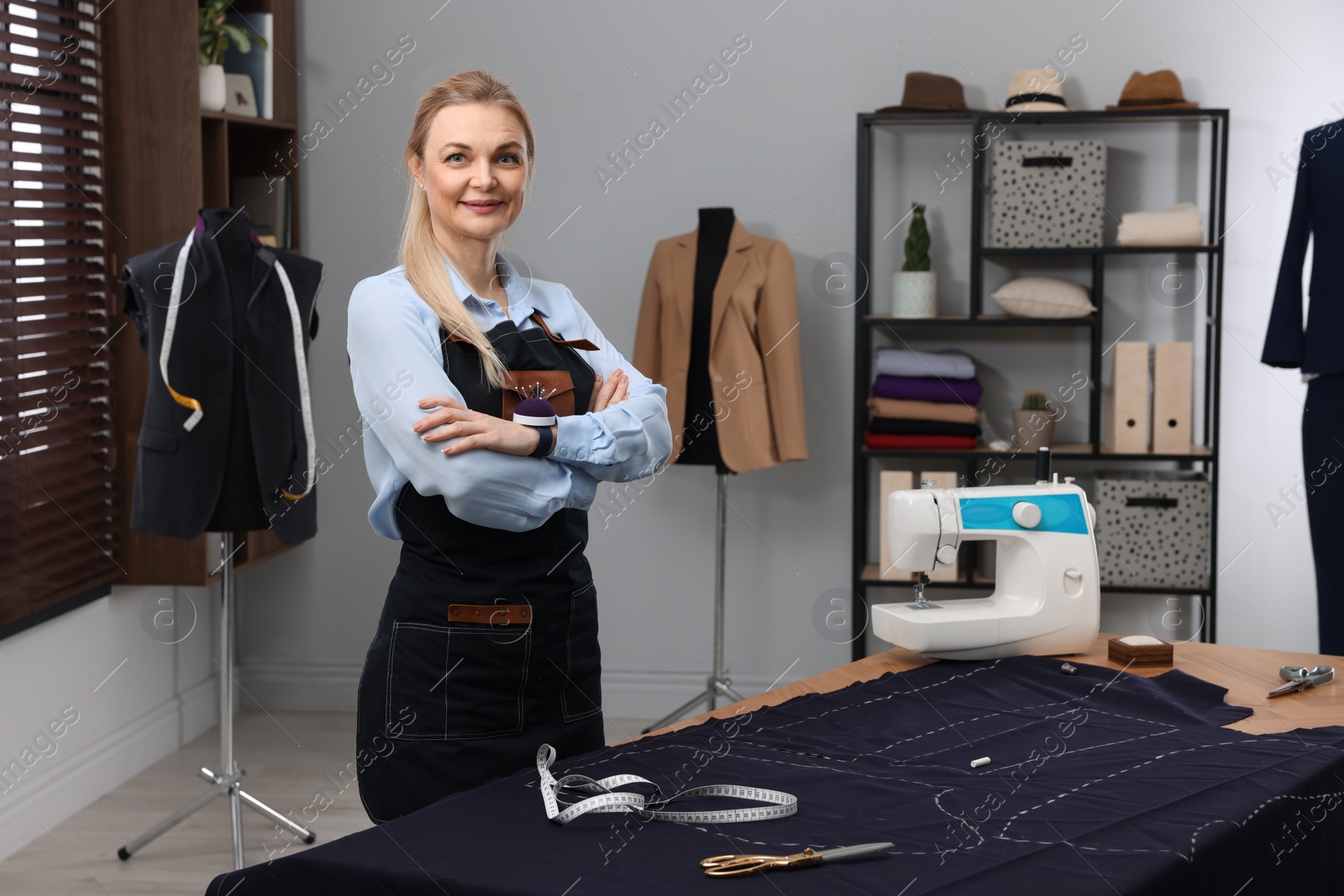 Photo of Portrait of professional dressmaker near table in workshop