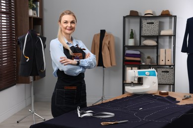 Photo of Portrait of professional dressmaker near table in workshop