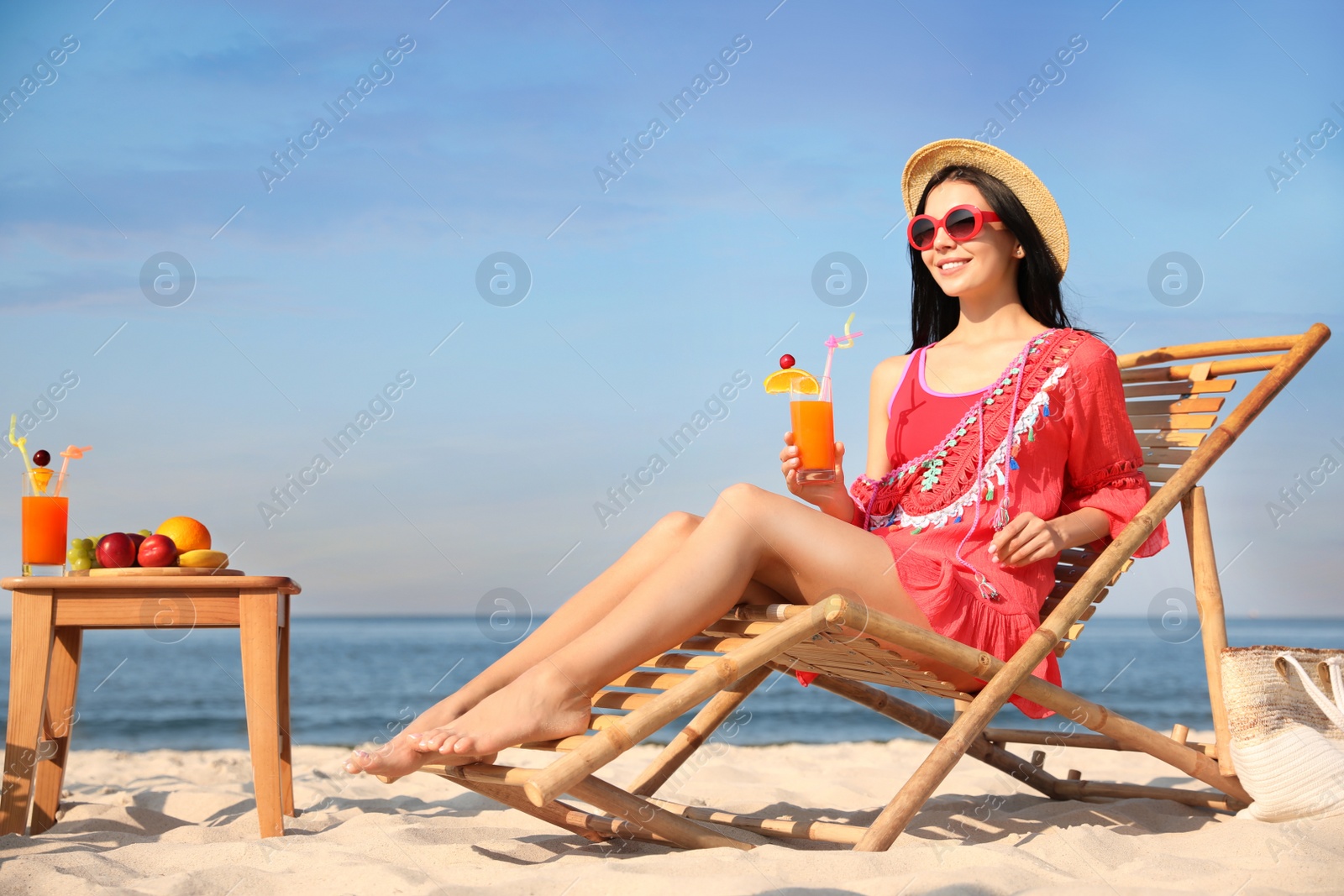 Photo of Beautiful woman in red dress resting on beach