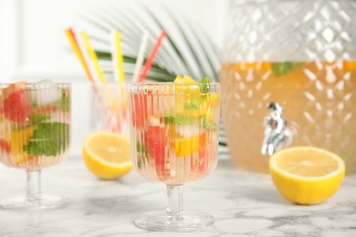 Photo of Delicious refreshing drink with orange and grapefruit on white marble table