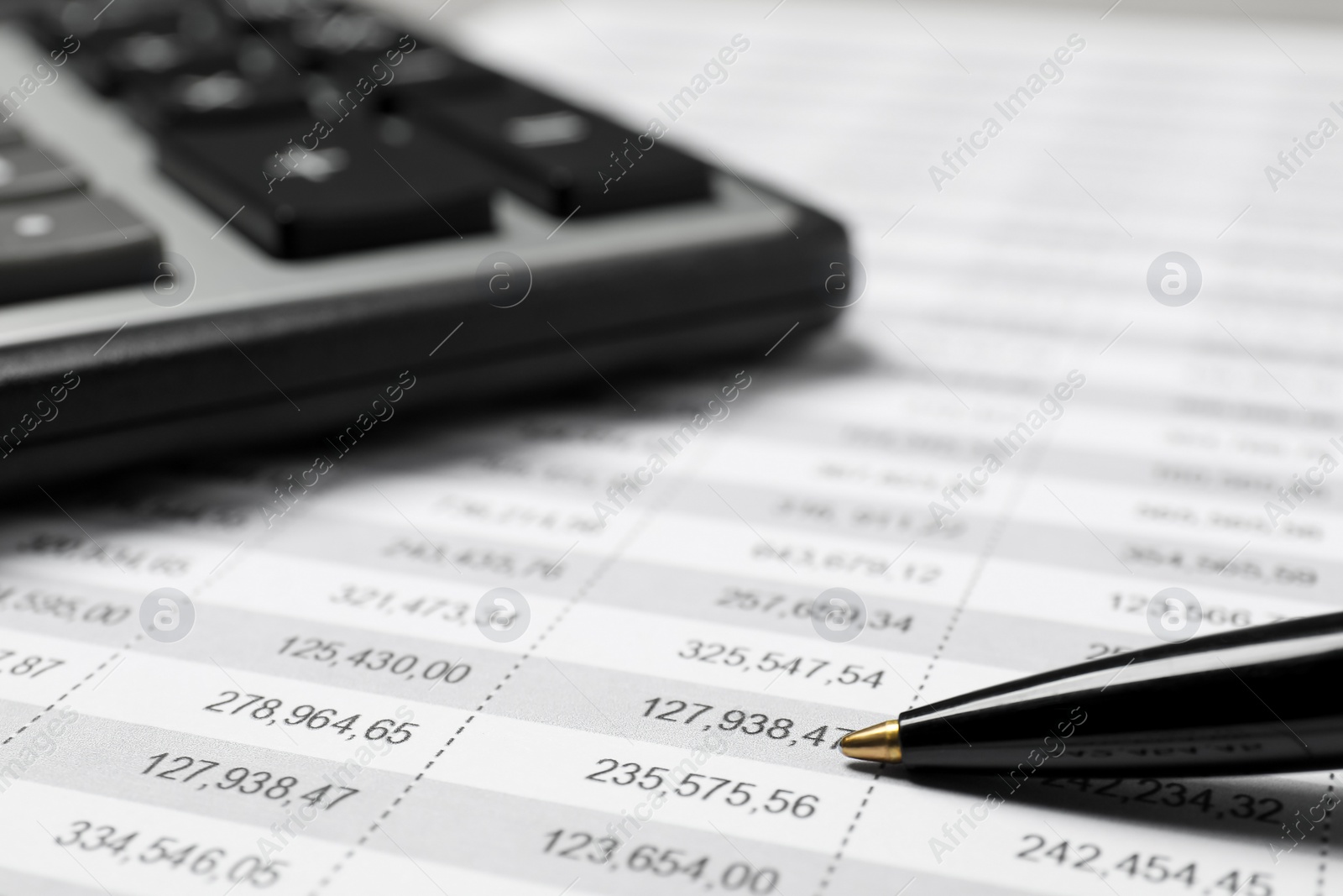 Photo of Calculator and pen on document with financial calculations, closeup