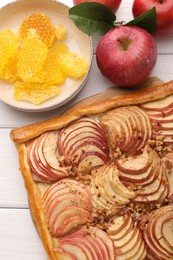 Tasty fresh apple galette and ingredients on white wooden table, flat lay