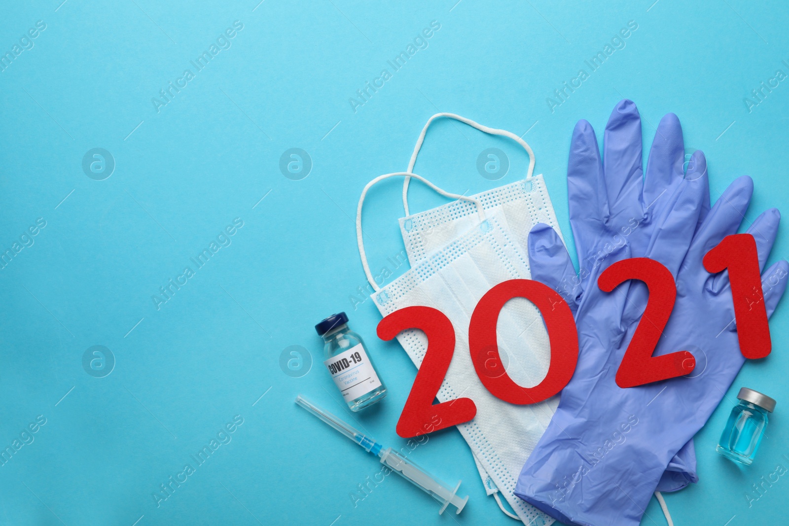 Photo of Flat lay composition with coronavirus vaccine and number 2021 on light blue background, space for text