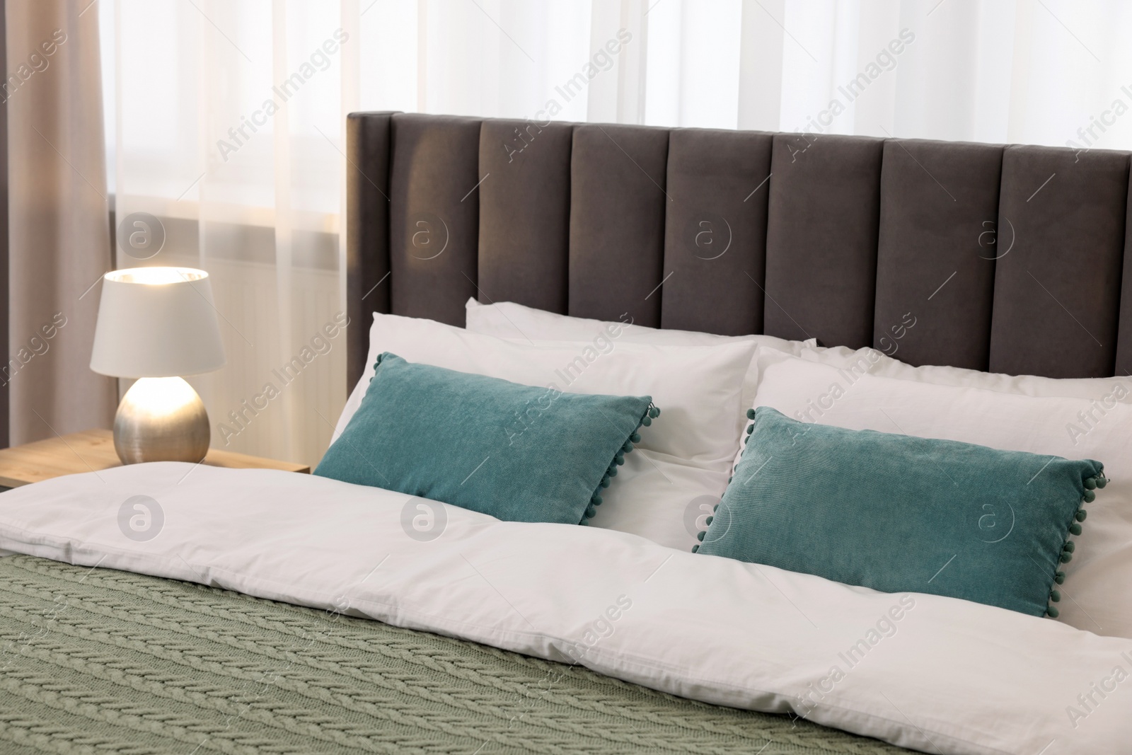 Photo of Comfortable bed with bedding and lamp in room