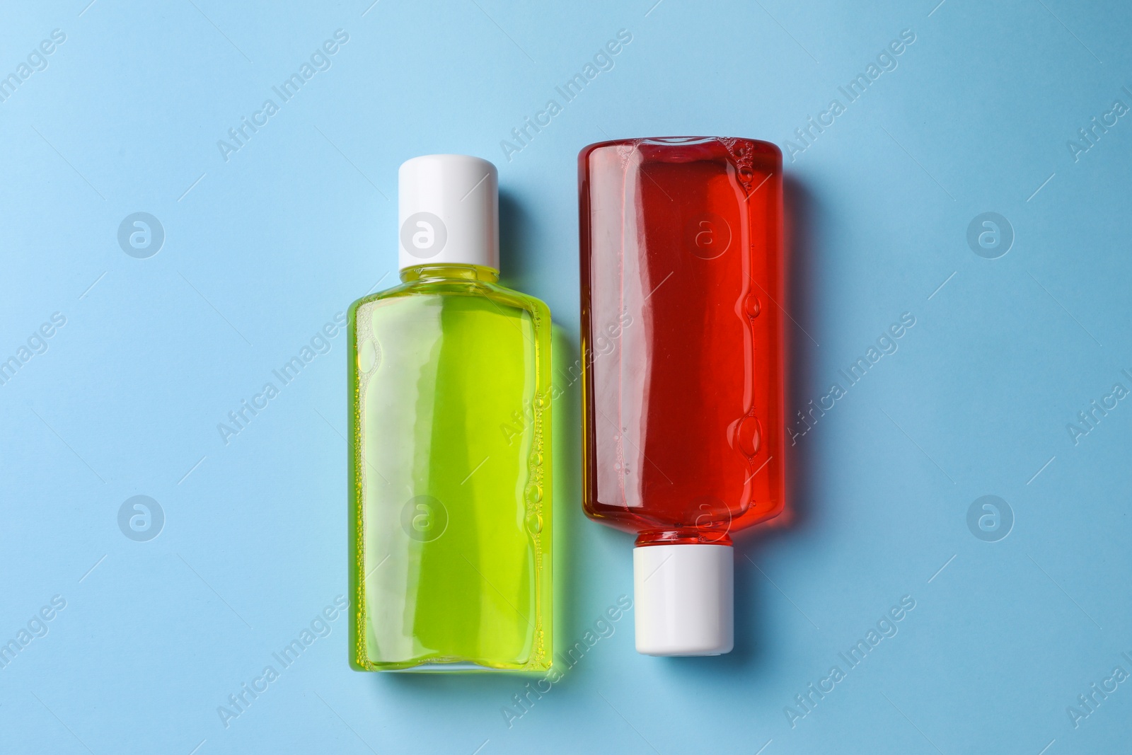 Photo of Fresh mouthwashes in bottles on light blue background, top view
