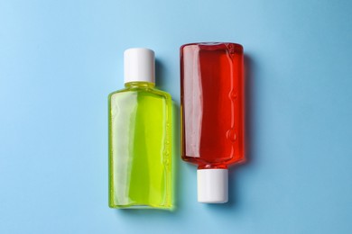 Fresh mouthwashes in bottles on light blue background, top view