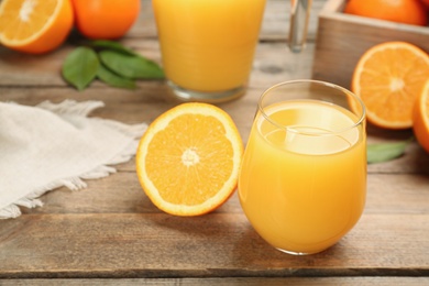 Photo of Delicious orange juice and fresh fruit on wooden table