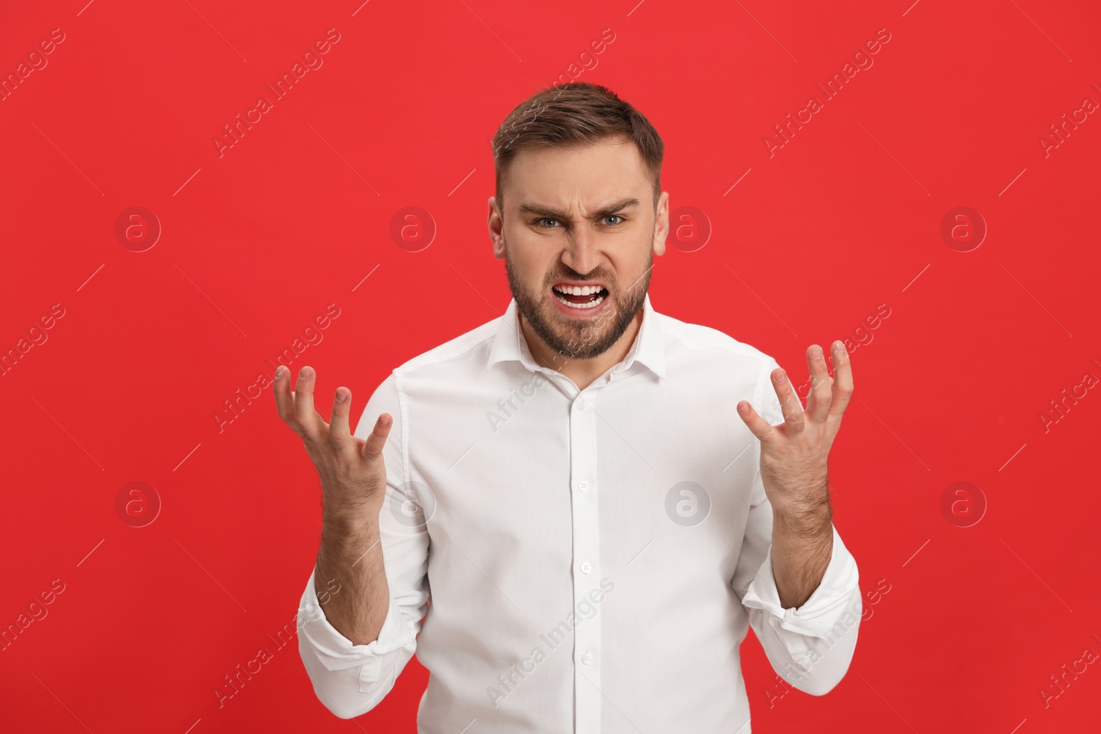 Photo of Angry young man on red background. Hate concept