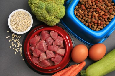 Photo of Raw meat in bowl and healthy products for pet on black background, flat lay