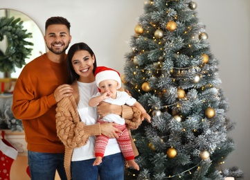 Photo of Happy family with cute baby near Christmas tree at home