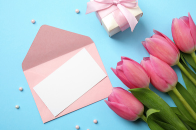 Photo of Flat lay composition with tulips and card on light blue background, space for text. Happy Mother's day