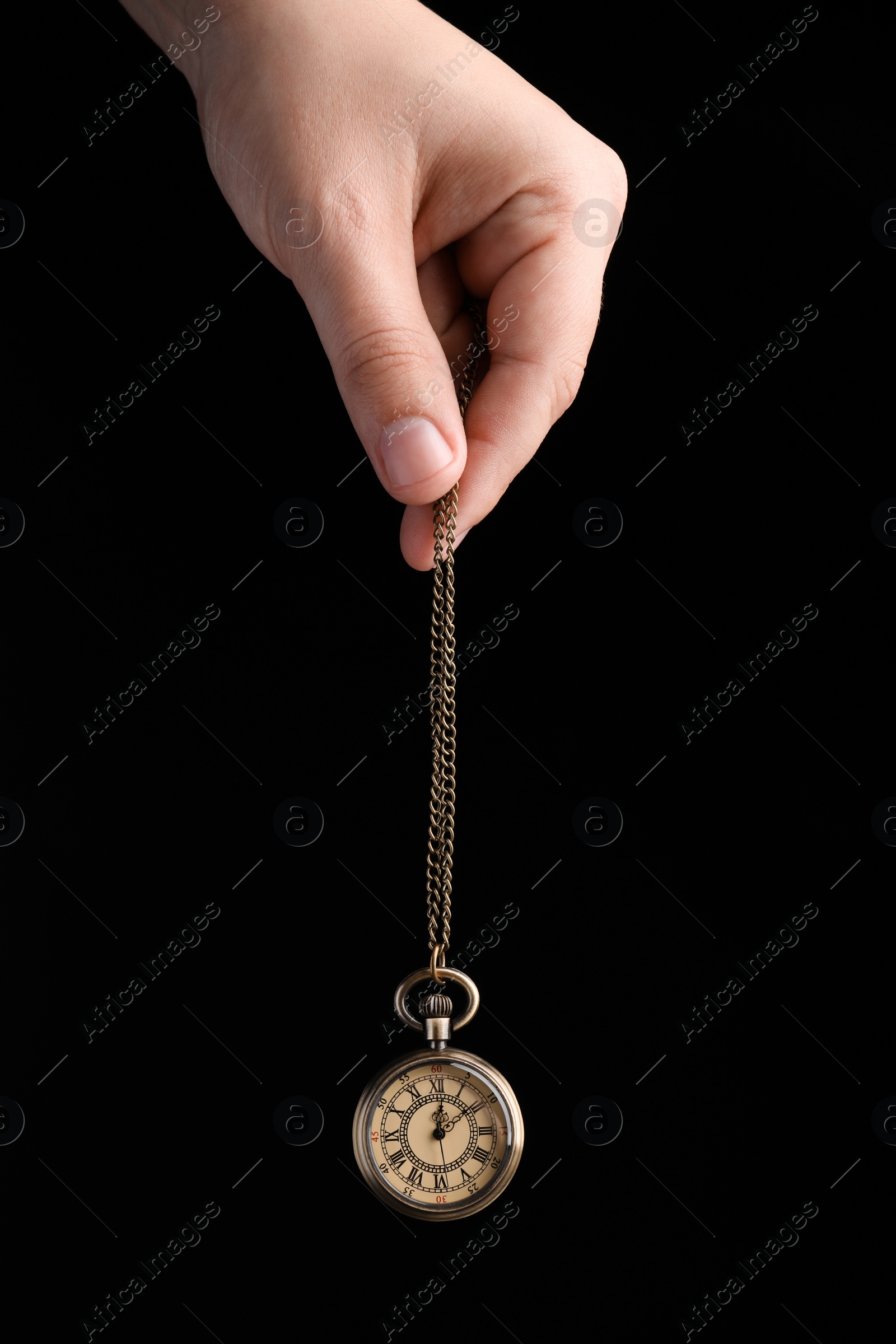 Photo of Psychotherapist with pendulum on black background, closeup. Hypnotherapy session