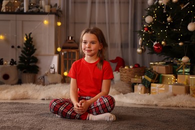 Photo of Cute little child in room with Christmas tree