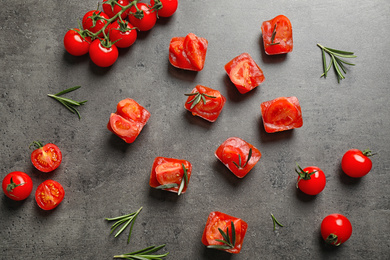 Ice cubes with tomatoes and rosemary on grey table, flat lay