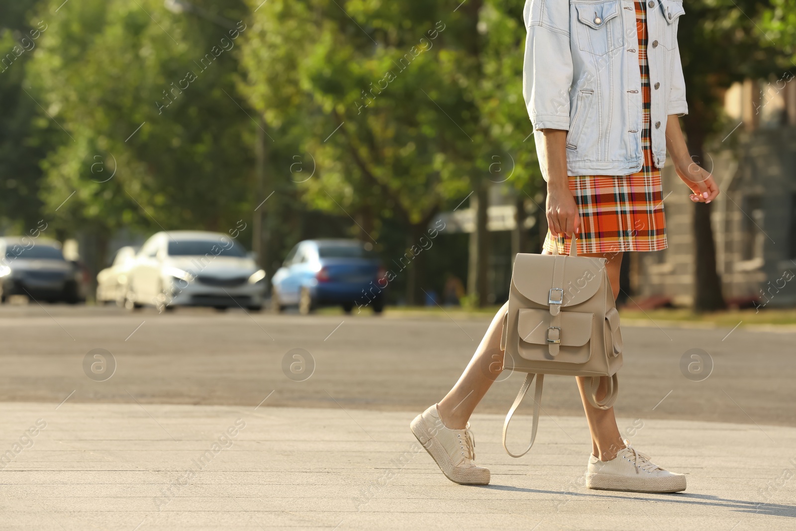 Photo of Young woman with stylish beige backpack on city street, closeup. Space for text
