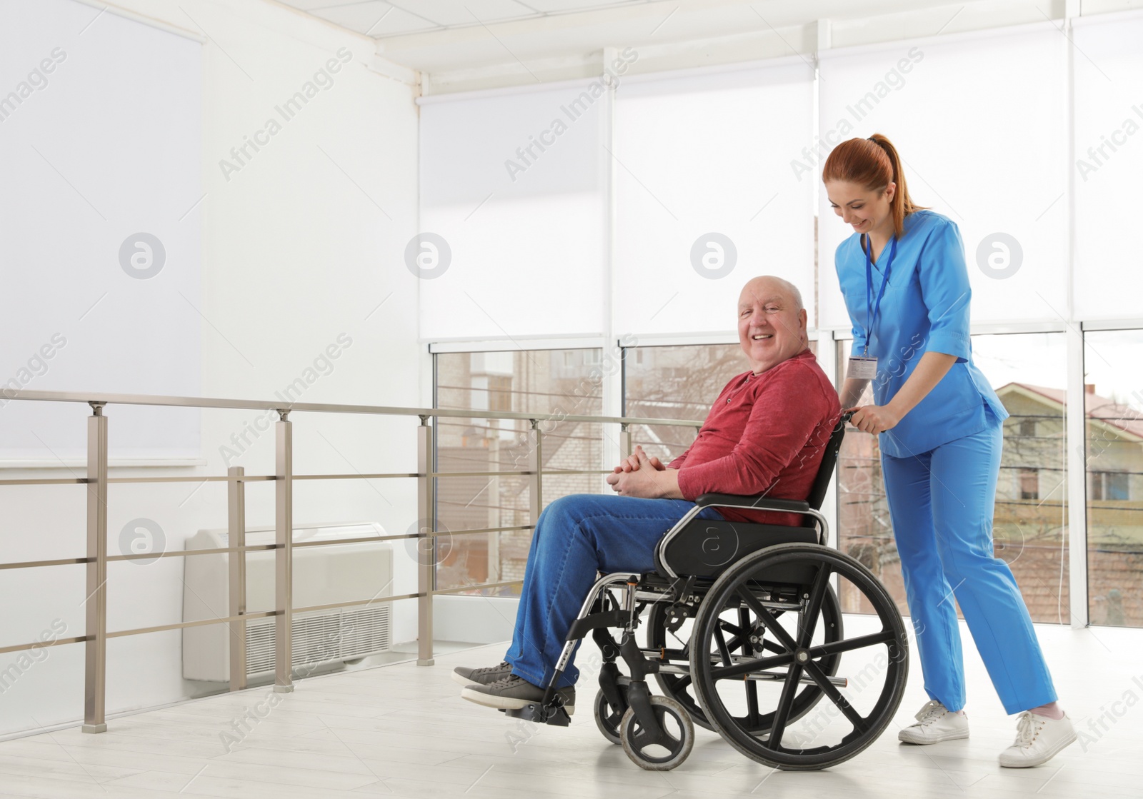 Photo of Nurse assisting senior man in wheelchair at hospital