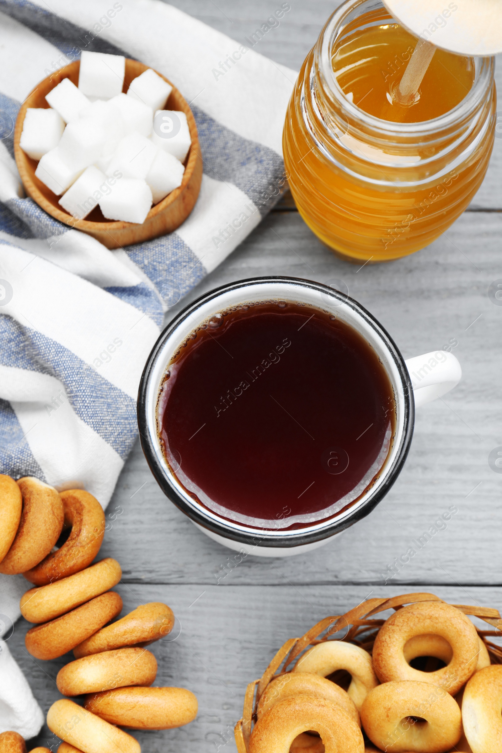 Photo of Flat lay composition with delicious ring shaped Sushki (dry bagels) and mug of tea on light grey wooden table