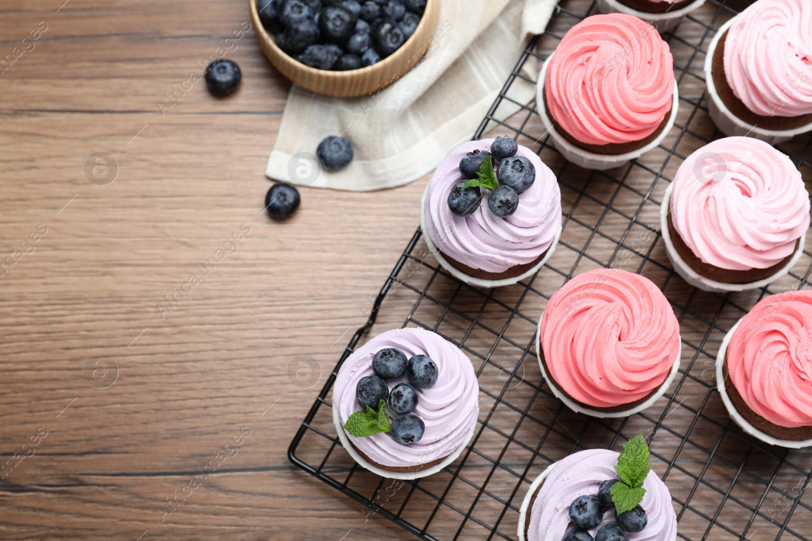 Photo of Sweet cupcakes with fresh blueberries on wooden table, flat lay. Space for text