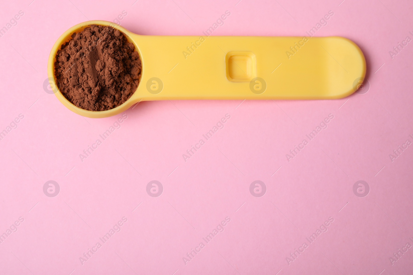 Photo of Spoon of protein powder on pink background, top view with space for text