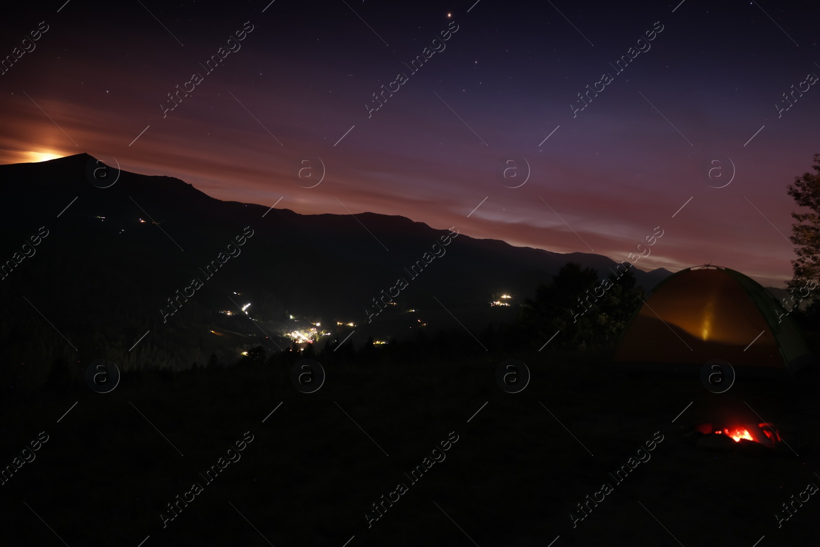 Photo of Beautiful view of mountain landscape with bonfire and camping tent in twilight