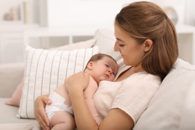 Photo of Mother holding her cute newborn baby on sofa indoors, space for text