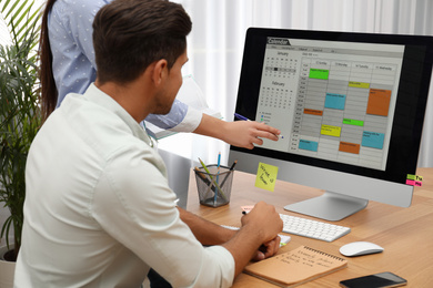 Colleagues working with calendar app on computer in office