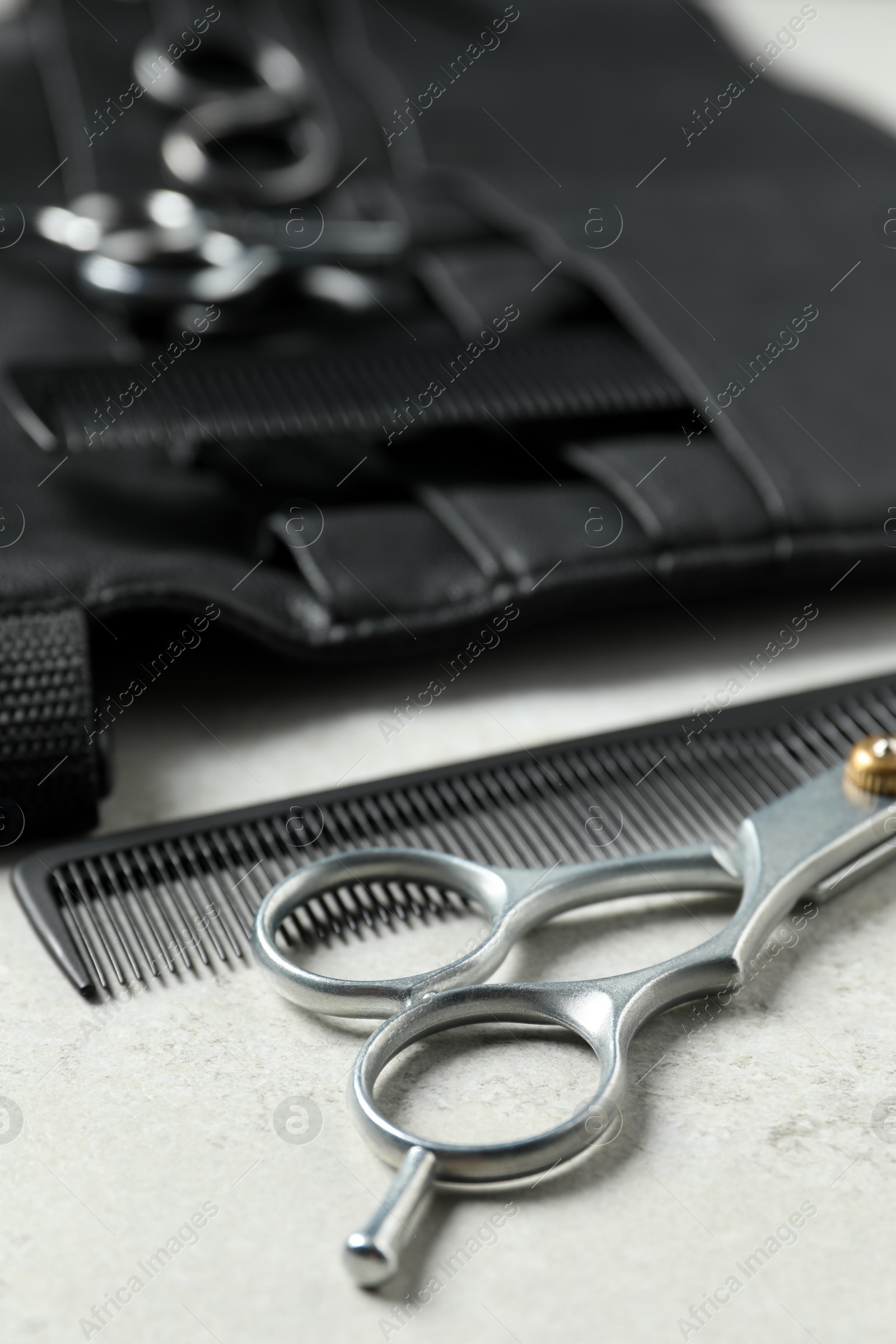 Photo of Hairdresser tools. Professional scissors, combs and leather organizer on white table, closeup