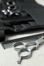Photo of Hairdresser tools. Professional scissors, combs and leather organizer on white table, closeup