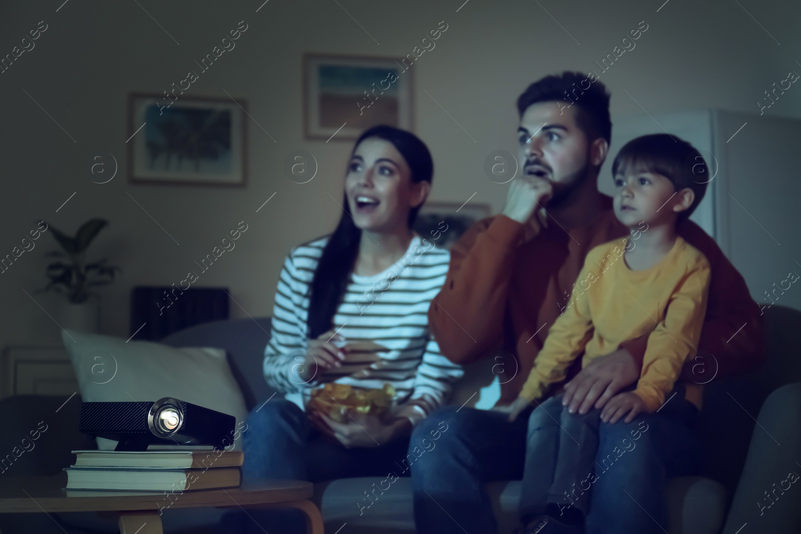 Photo of Emotional family watching movie at home, focus on video projector
