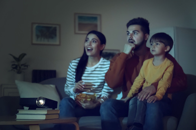 Photo of Emotional family watching movie at home, focus on video projector