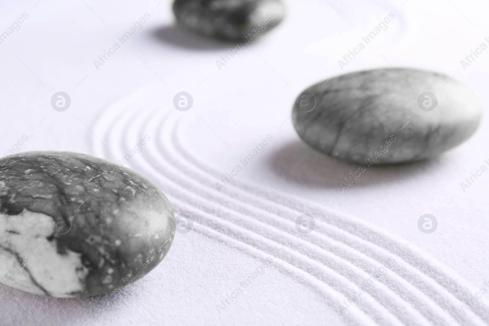 Photo of Zen concept. Stones and pattern on white sand, closeup