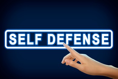 Image of Woman pointing at words Self Defense on virtual screen against blue background, closeup