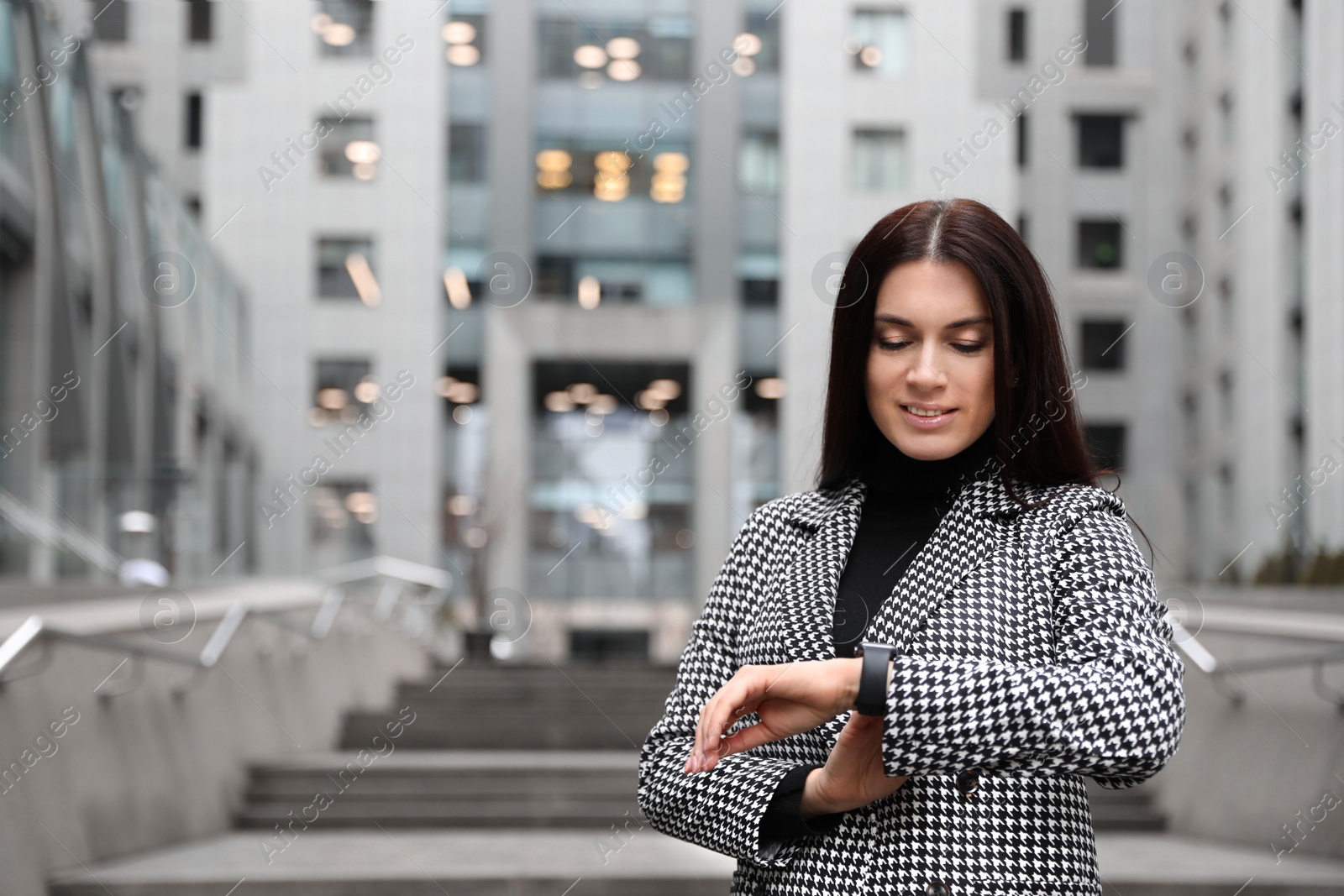 Photo of Beautiful woman in stylish suit checking time outdoors. Space for text