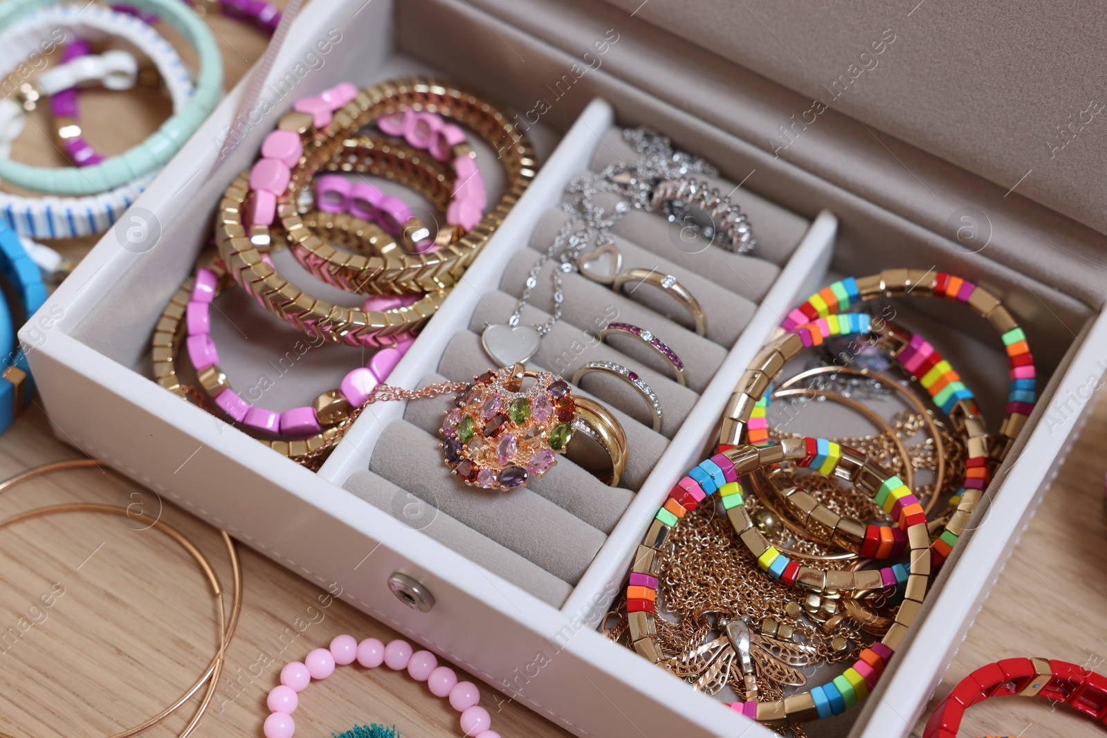 Photo of Jewelry box with stylish bracelets and other accessories on wooden table, closeup