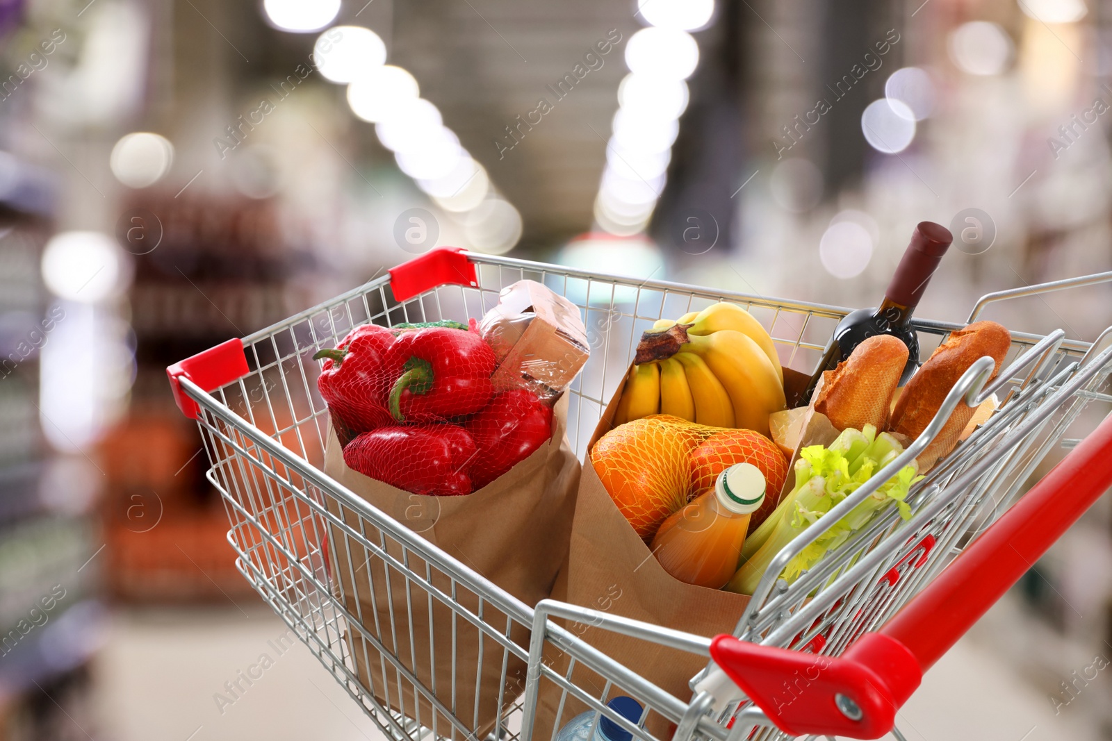 Image of Shopping cart with different groceries in supermarket