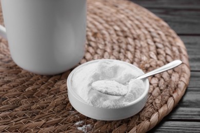 Bowl of fructose powder and cup with drink on dark wooden table, closeup