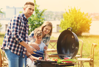 Happy family having barbecue with modern grill outdoors on sunny day
