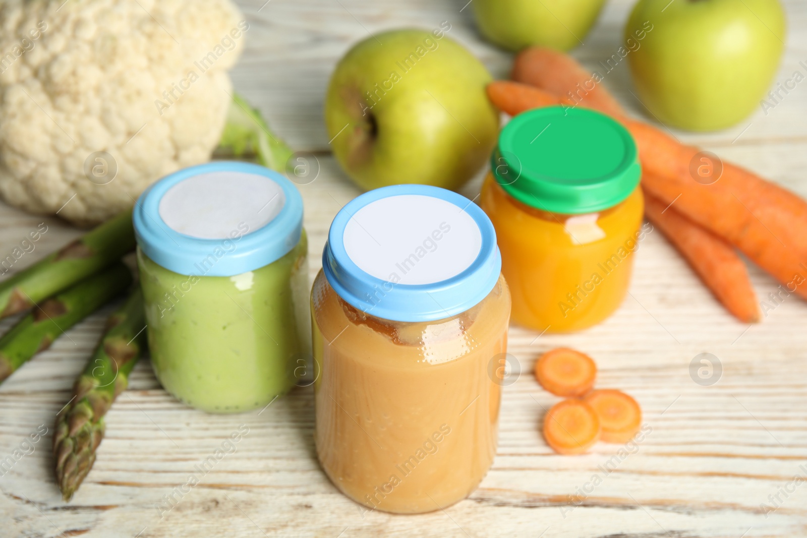 Photo of Jars with baby food and fresh ingredients on white wooden table