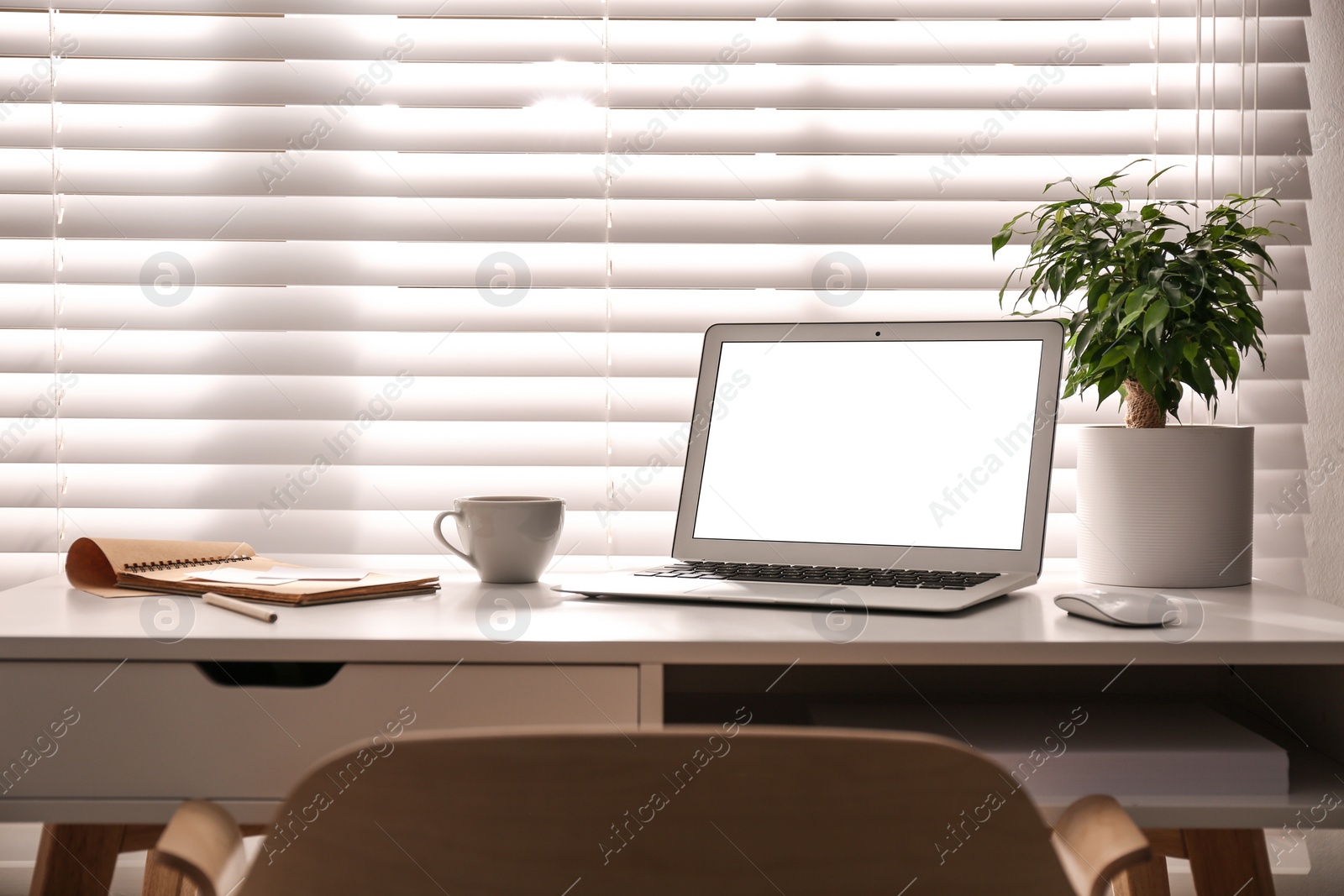 Photo of Laptop on desk near window in office. Comfortable workplace