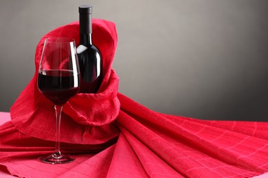 Photo of Stylish presentation of delicious red wine in bottle and glass on table against grey background. Space for text