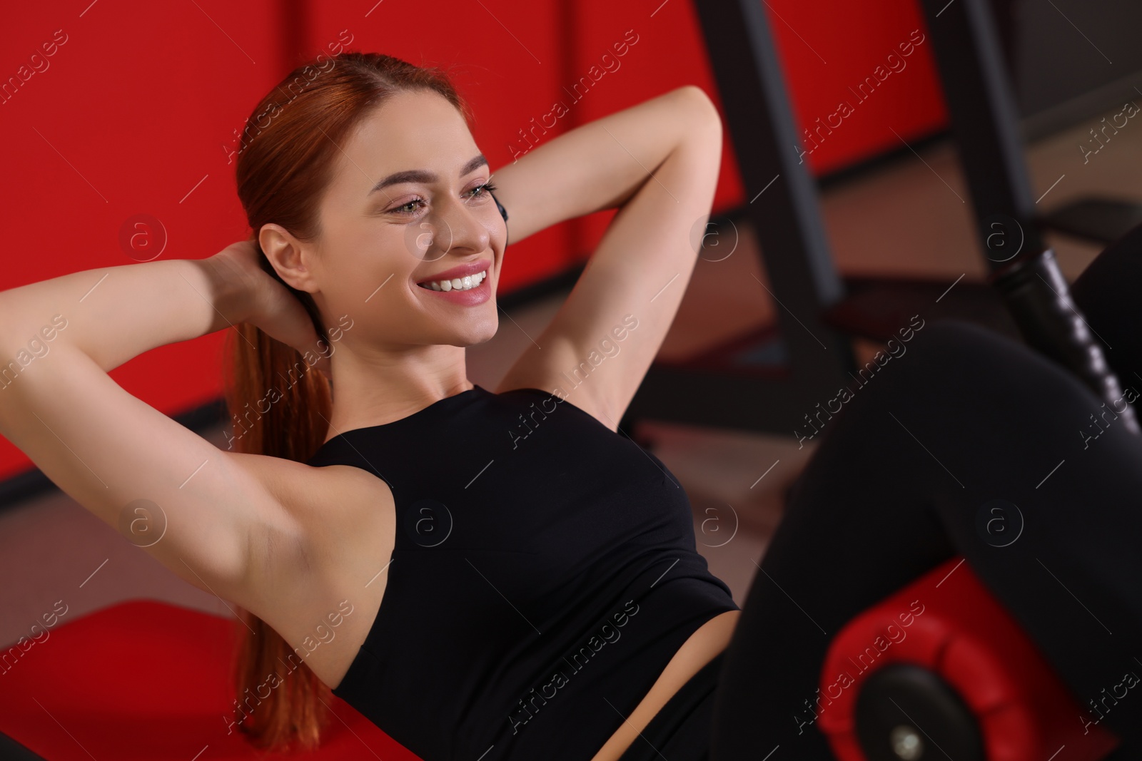 Photo of Athletic young woman pumping up abs on roman chair in gym