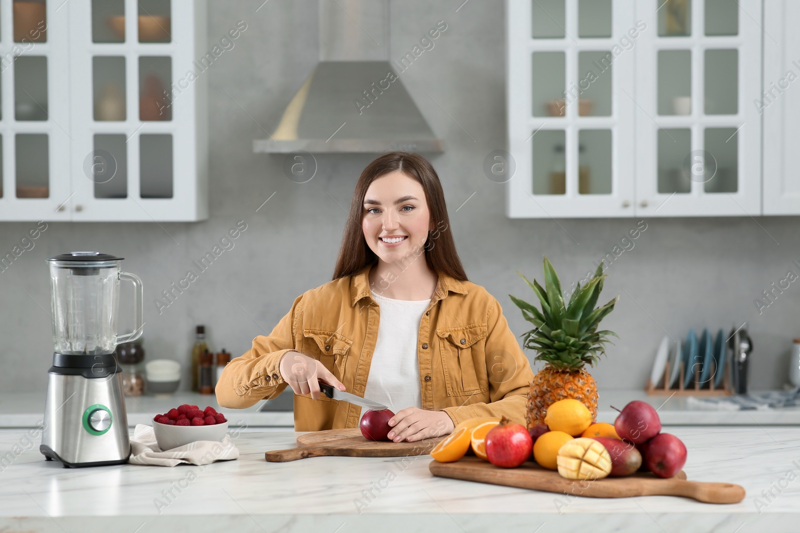 Photo of Woman preparing ingredients for tasty smoothie at white marble table in kitchen