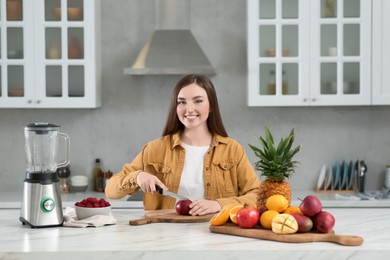 Photo of Woman preparing ingredients for tasty smoothie at white marble table in kitchen