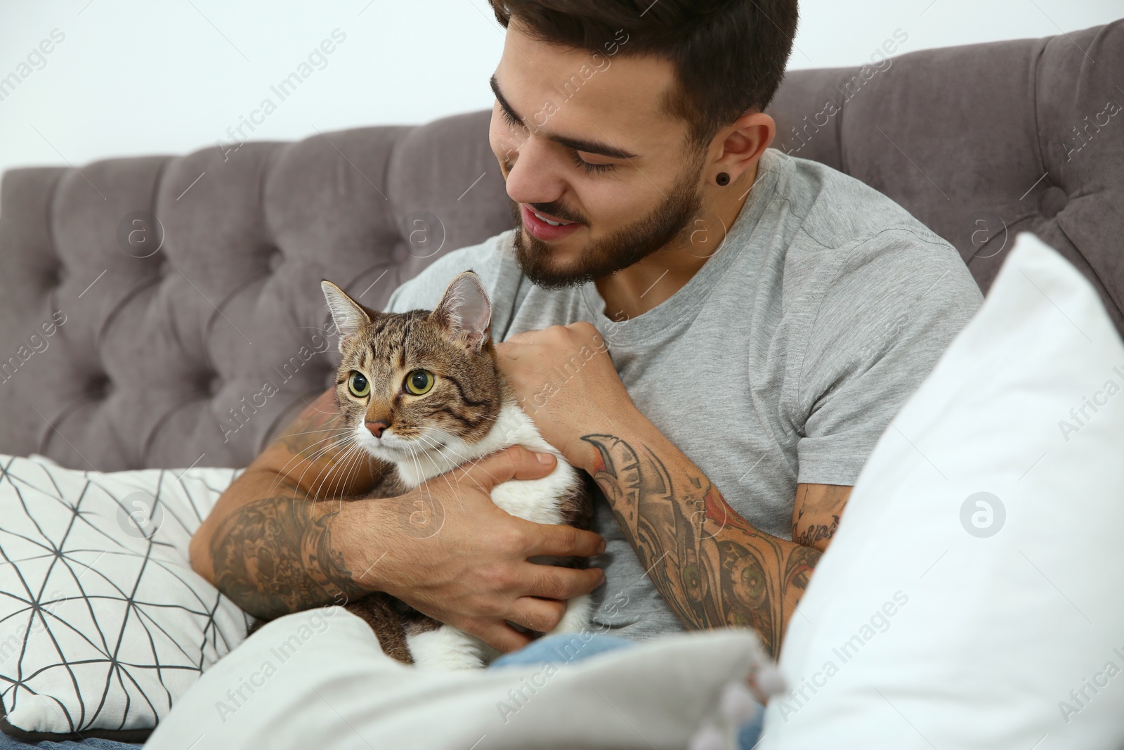 Photo of Happy man with cat on bed at home. Friendly pet