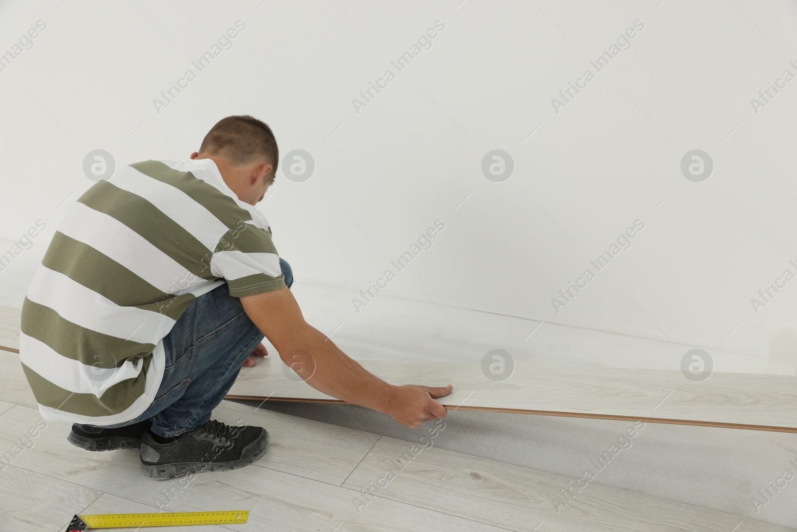 Photo of Professional worker installing new laminate flooring indoors