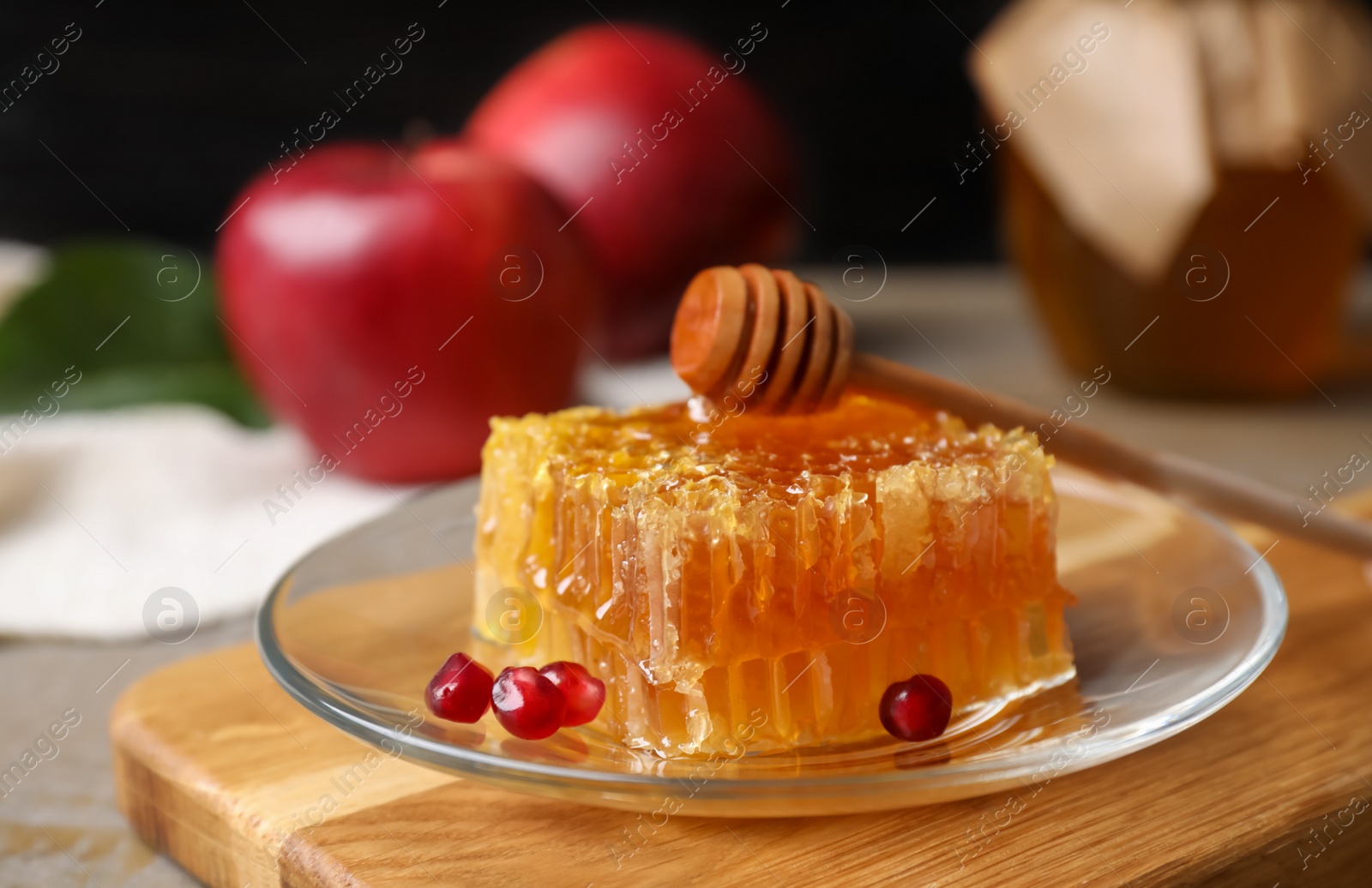 Photo of Honeycomb with pomegranate seeds near apples on wooden table, closeup. Rosh Hashanah holiday