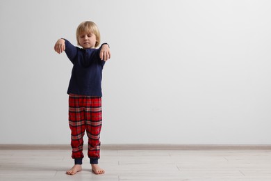 Boy in pajamas sleepwalking indoors, space for text
