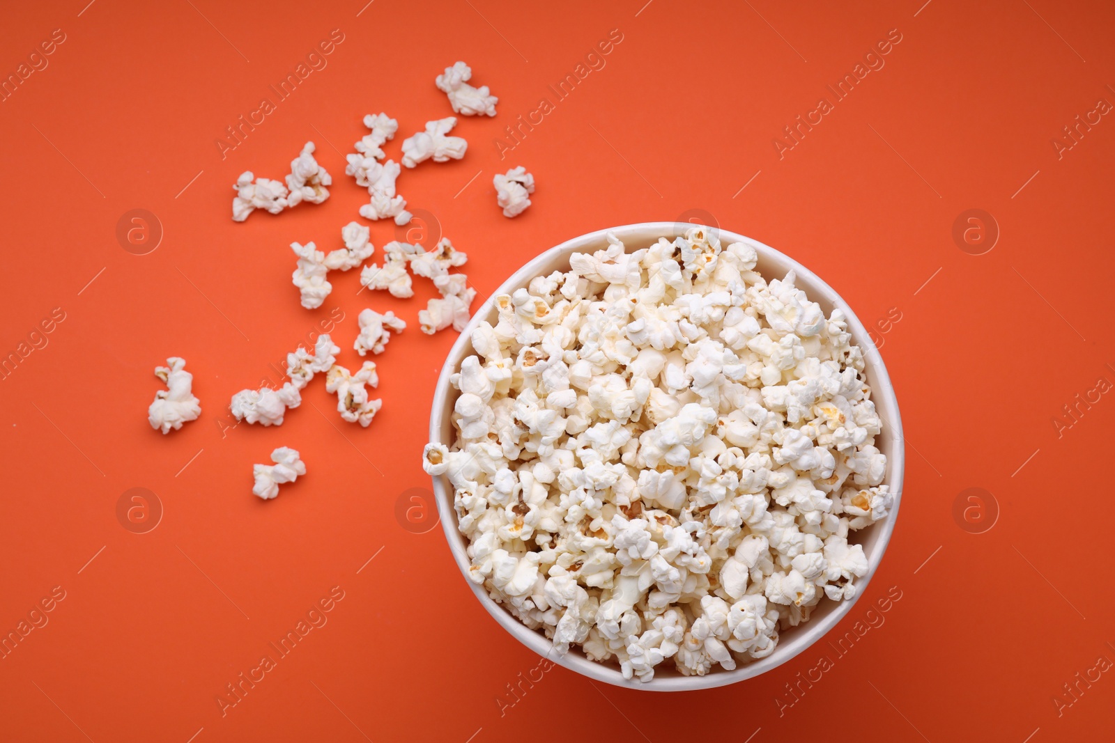 Photo of Bucket of tasty popcorn on orange background, flat lay