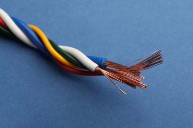 Many twisted electrical wires on blue background, closeup